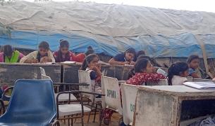 Young girls sit at tables at a makeshift migrant learning center in Delhi