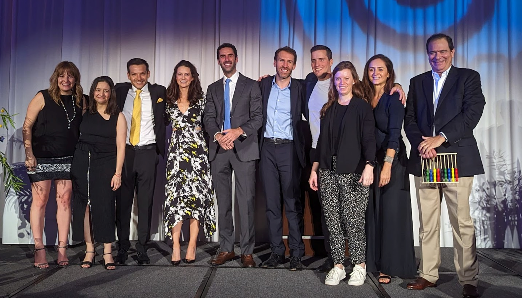 A row of professionally dressed men and women stand together on a stage