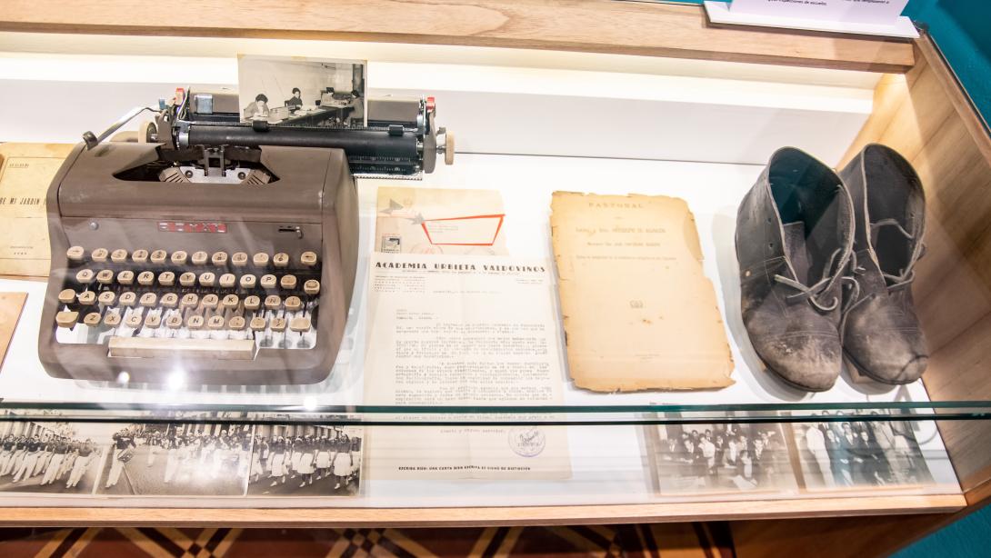 Museum  display case with a typwriter, document and shoes inside