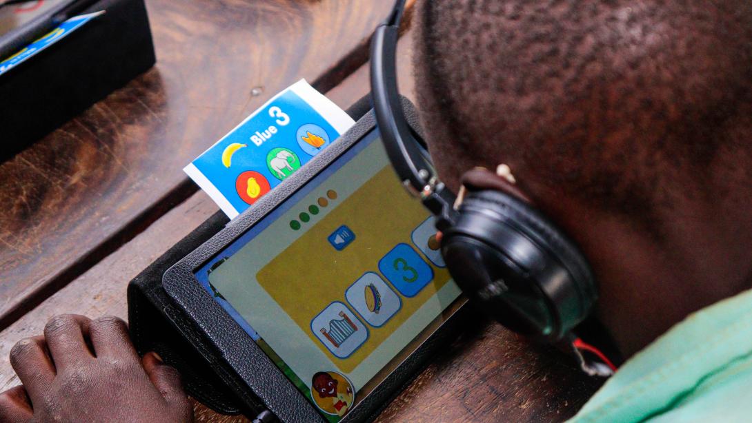 An African student with headphones on works on a tablet