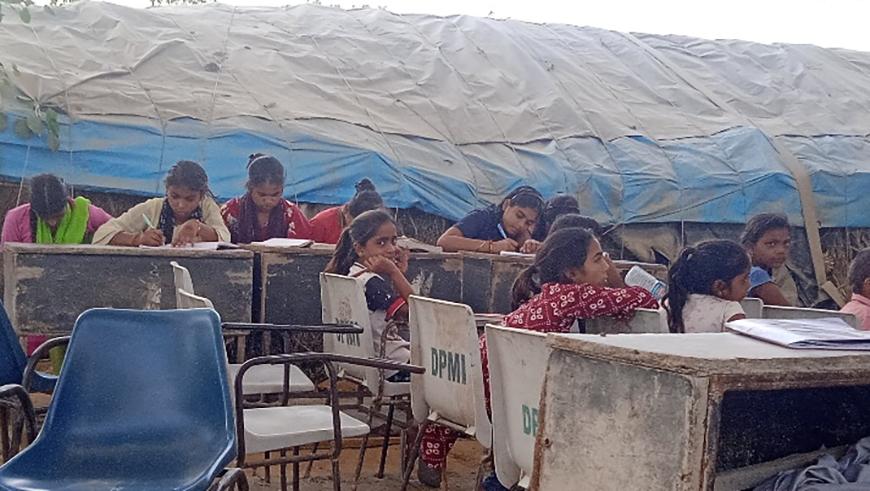 Young girls sit at tables at a makeshift migrant learning center in Delhi